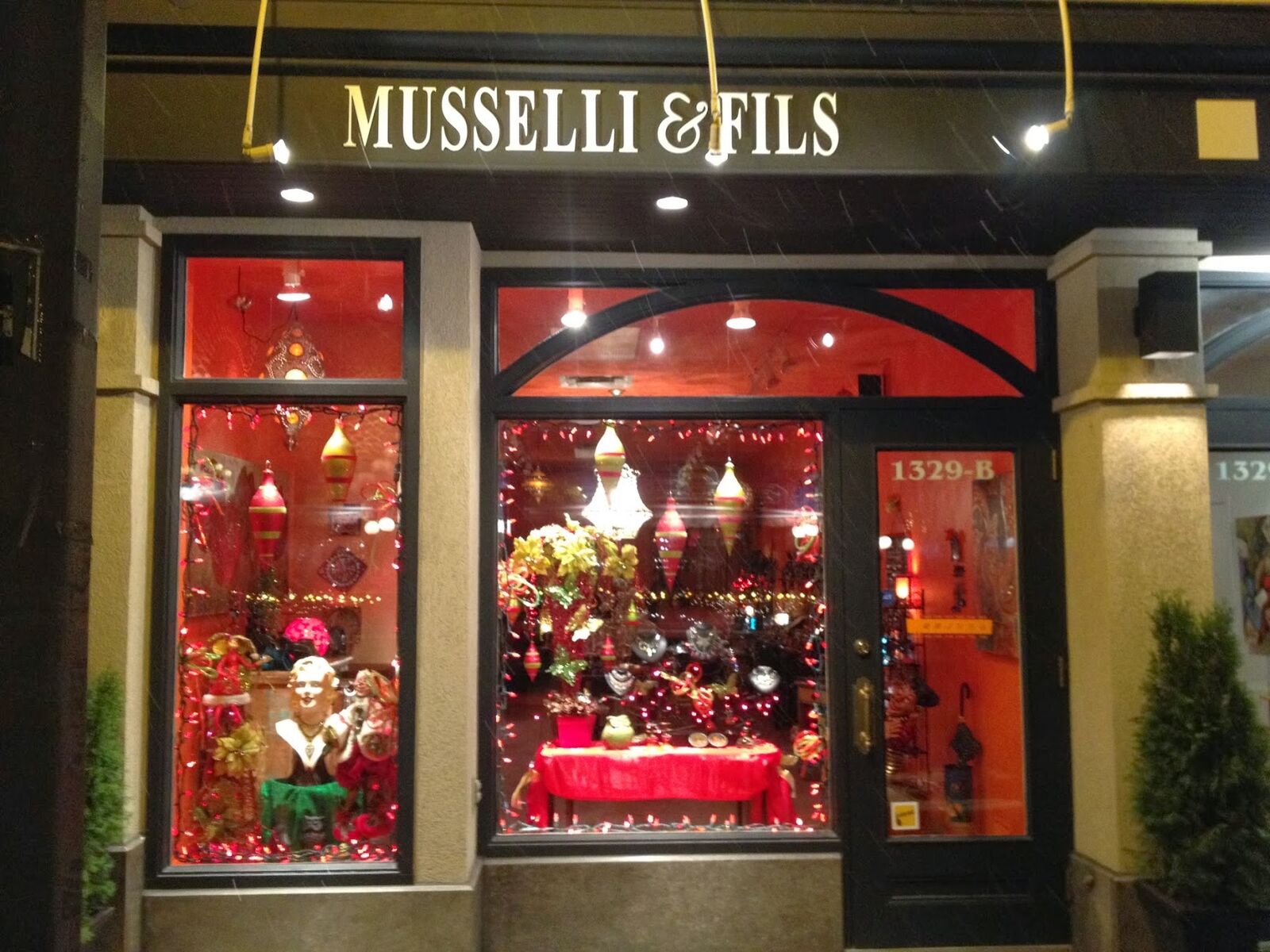 La vitrine illuminée de Musselli & Fils, le soir, au 1329-B avenue Maguire